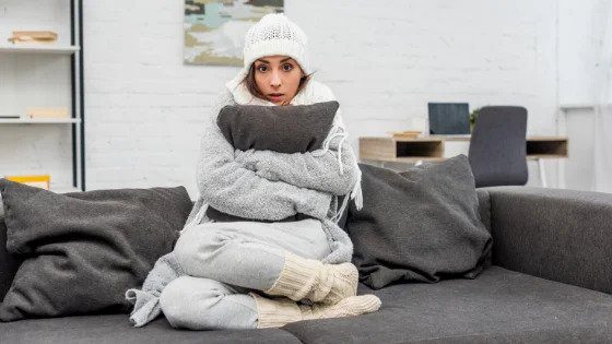 A cold woman in a local home with warm clothes and a blanket