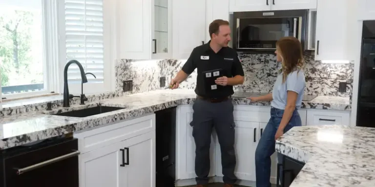 A friendly team member reviews recent plumbing repairs with a customer in a bright kitchen, showcasing Black Diamond Experts’ trusted 24/7 service.