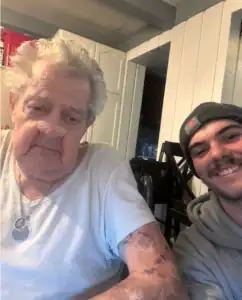 A smiling elderly person and a younger companion sit together in a bright room, reflecting trusted, caring home service expertise.