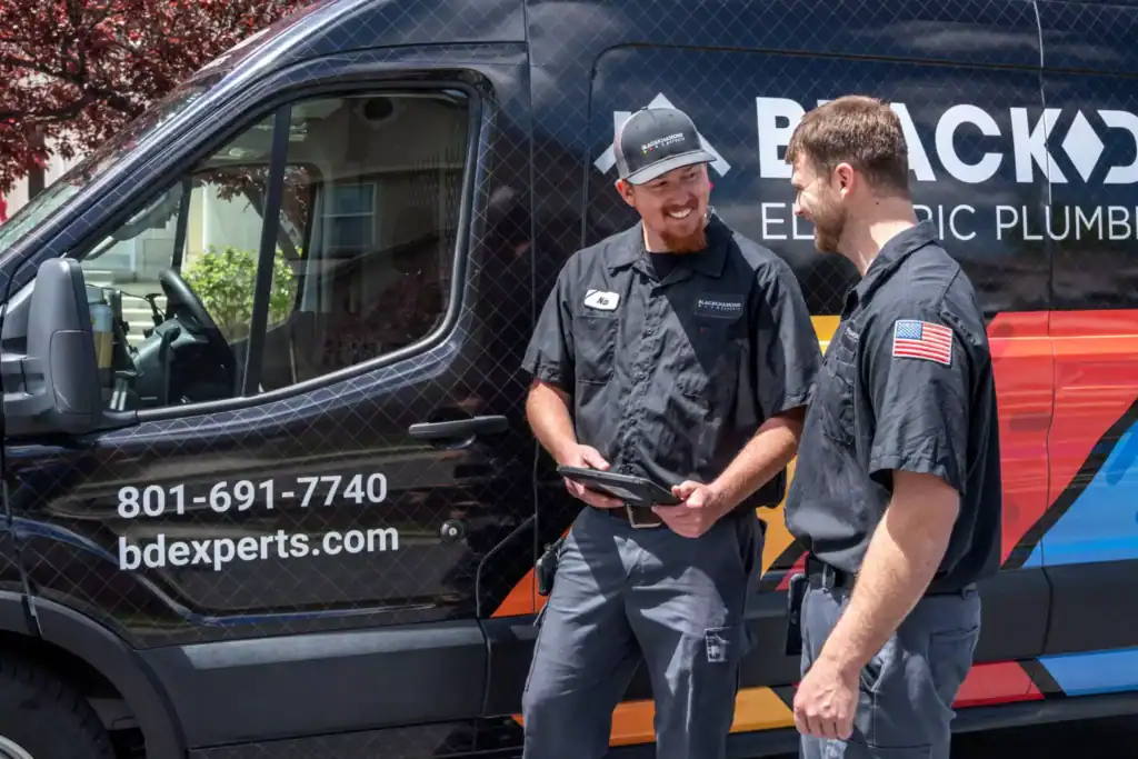 Two skilled Black Diamond Experts technicians stand by a service van, ready to provide Utah’s trusted 24/7 plumbing, HVAC, and electrical care.