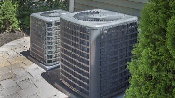 Two outdoor AC units rest on sturdy pads by a home, reflecting Black Diamond Experts’ trusted 24/7 comfort and repair services.