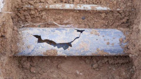 A cracked underground pipe exposed in a dirt trench, ready for expert repair by Utah’s trusted 24/7 Black Diamond Experts team.