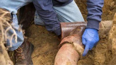 A skilled technician in gloves and boots expertly repairs a buried pipe, ensuring safe, reliable home service—anytime, 24/7.