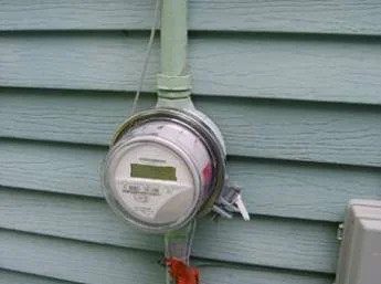 A modern utility meter on a light blue home’s siding, reminding you Black Diamond Experts are here 24/7 for all home services.