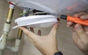 A skilled Black Diamond Experts technician safely repairs electrical wiring under a sink, ensuring reliable 24/7 home comfort.