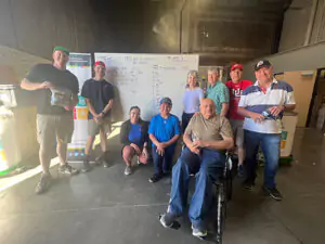 Nine Black Diamond Experts, including a team member in a wheelchair, pose warmly in their warehouse, ready to serve Utah 24/7.