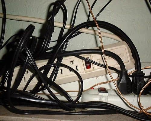 Black cords connect to a white power strip against a pale wall—trust Black Diamond Experts for safe, 24/7 electrical solutions.