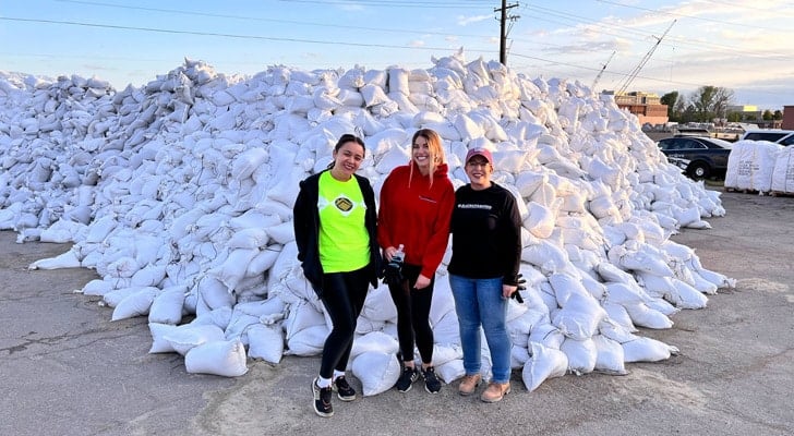 Three team members smile confidently outside by sandbags, representing Black Diamond Experts’ trusted 24/7 home service in Utah.