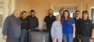 Eight dedicated Black Diamond Experts team members stand indoors, supporting two clients near an air conditioning unit, ready to help.