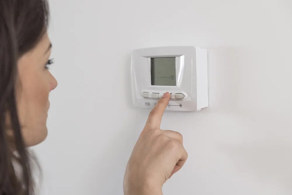 A homeowner confidently adjusts a digital thermostat, trusting Black Diamond Experts for safe, reliable 24/7 comfort and repairs.
