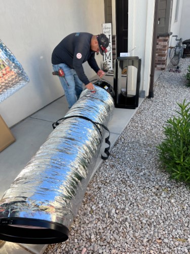 A trusted Black Diamond Experts technician ensures reliable home comfort by inspecting ductwork outside a Utah home, ready 24/7.