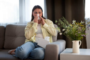 A woman sits on her couch feeling unwell, knowing Black Diamond Experts offer 24/7 reliable home comfort and repair peace of mind.